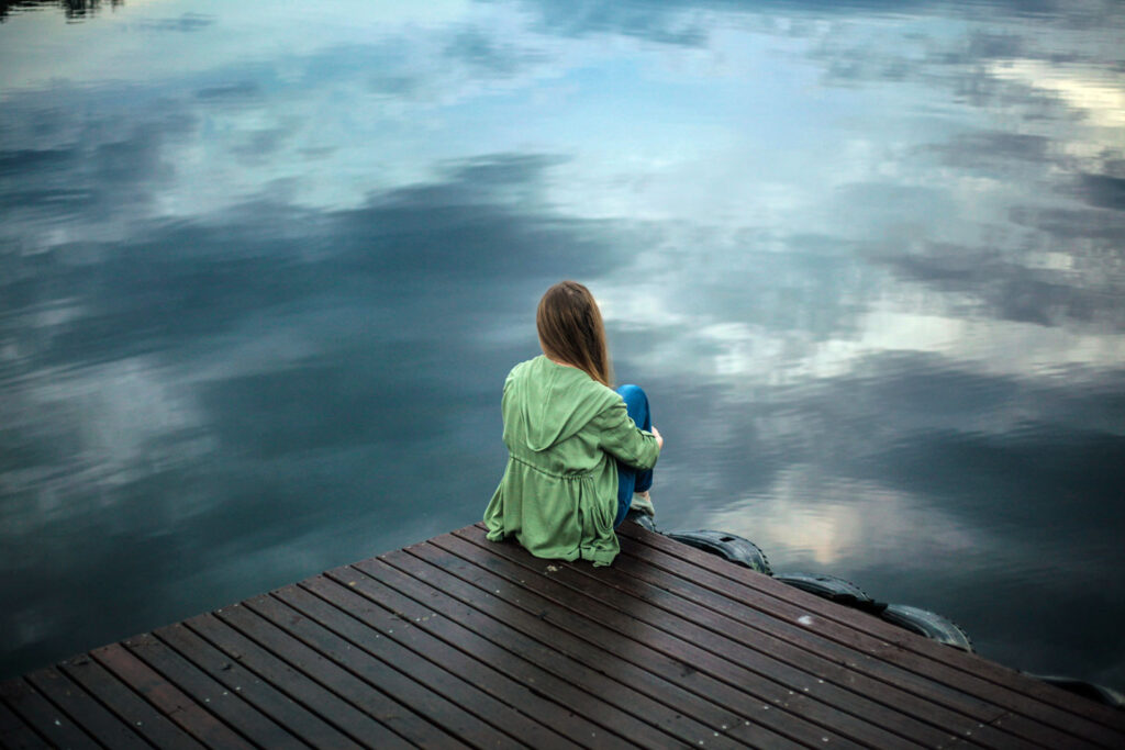 Woman sitting on a wooden dock overlooking the lake
