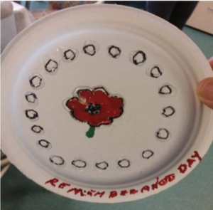a paper plate with a drawing of a poppy and writing that says "remembrance day"