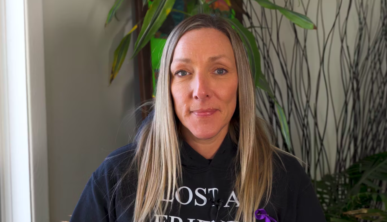 a white woman with long, blonde hair wearing a black hoodie smiles gently into the camera.