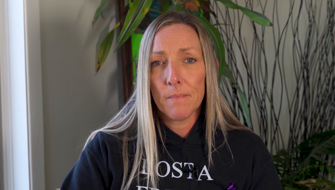 a white woman with long, blonde hair wearing a black sweatshirt looks into the camera.