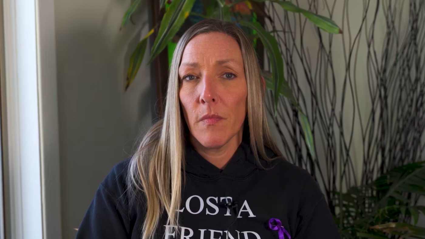 a white woman with long, blonde hair wearing a black sweatshirt looks into the camera.