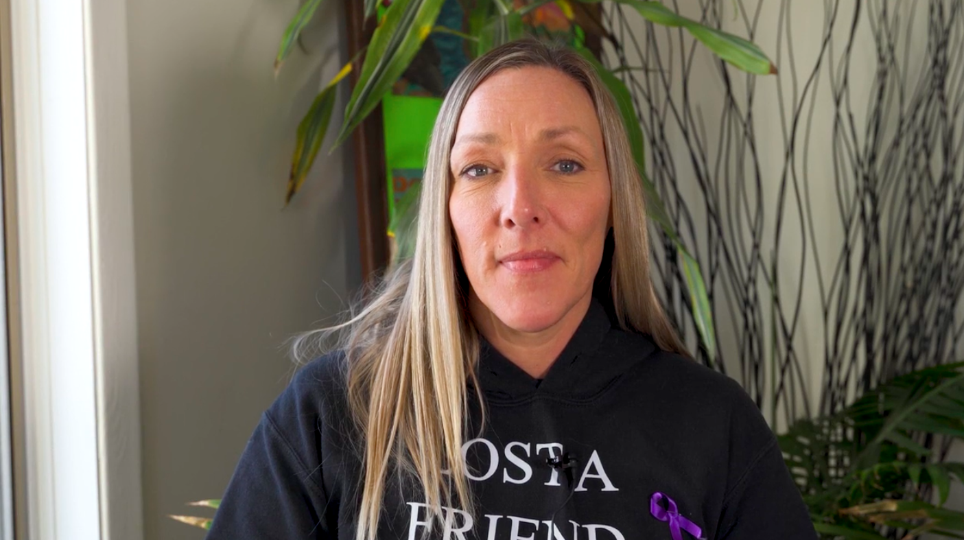 a white woman with long blonde hair wearing a black sweatshirt looks into the camera.