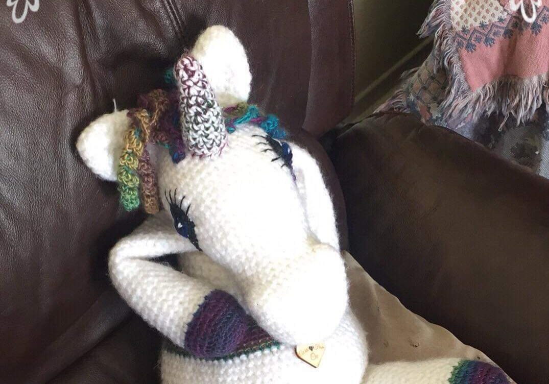 a crochet unicorn sitting on a couch